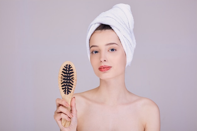 Beautiful lady after a shower holds a wooden comb in her hands.