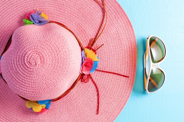 Beautiful lady beach hat with sunglasses on blue wooden background