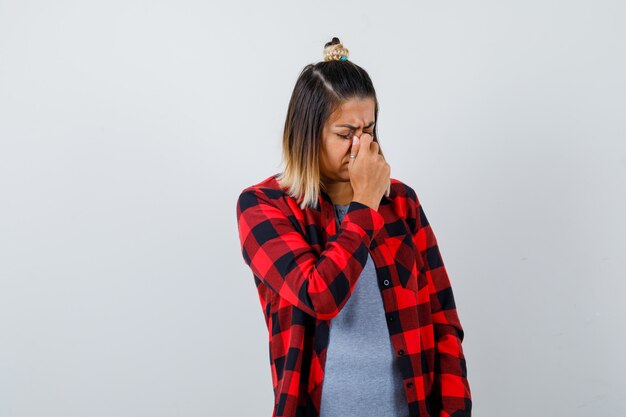 Beautiful lady in casual clothes rubbing nose and looking distressed , front view.