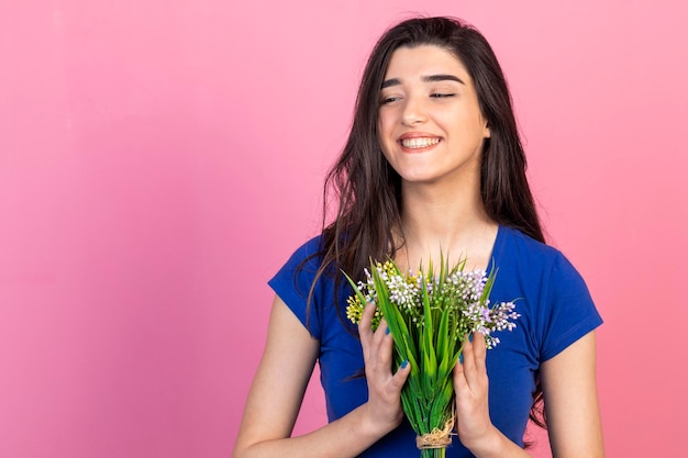 Una bella signora che tiene un mazzo di fiori con entrambe le mani e sorridente