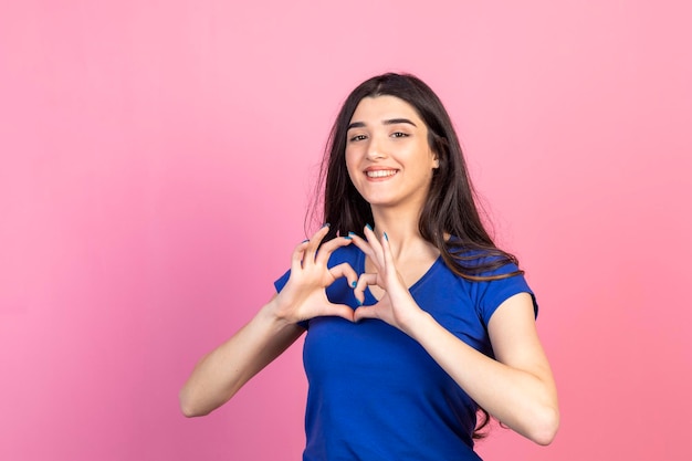 Bella signora che tiene le sue mani come un cuore e sorridente