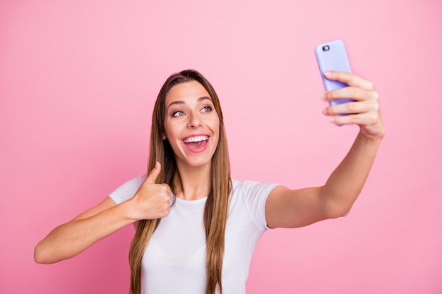  of beautiful lady holding telephone taking selfies raising thumb finger up modern blogger giving feedback wear casual white t-shirt 