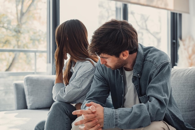 beautiful lady is depressed sitting on the couch talking to man having a dispute with husband or boyfriend looking desperate and hopeless having unresolved problem or questionxa