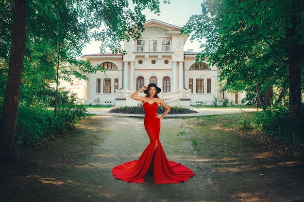 美しい女性はセクシーな赤いドレスでポーズをとってください。