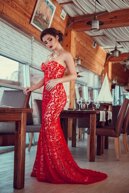 Красивая дама в красном платье в ресторане.