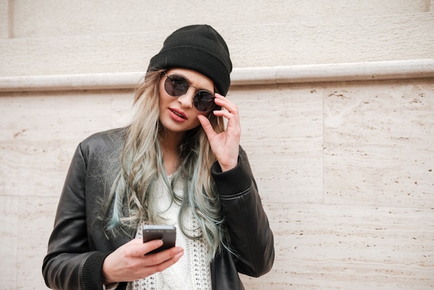 Beautiful lady wearing hat and sunglasses walking on the street.