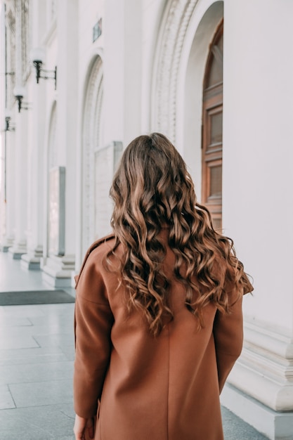 The beautiful lady with curly hair. the back view of a girl. woman walking down the street. traveler, summer fashion trend