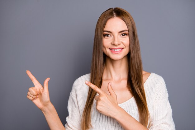 Beautiful lady with long hair posing against the grey wall