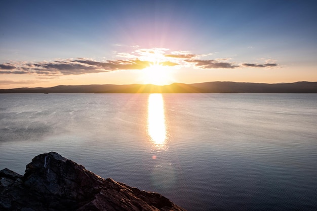 Beautiful lake and rocky shore in the rays of evening sun of golden autumn