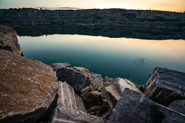 Beautiful lake surrounded by large piles of stone waste from hard work in a mine against a beautiful night sky with stars