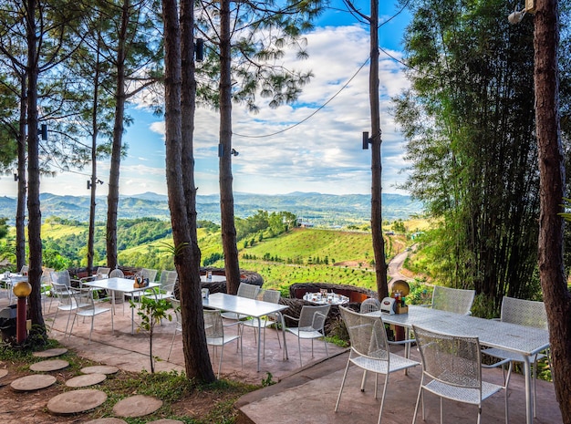 야외 산 전망을 배경으로 테이블과 의자 테라스가 있는 카페 스타일의 아름다운 풍경.