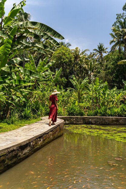 Photo beautiful landscape. cute young female person standing near lake while looking at fishes in water