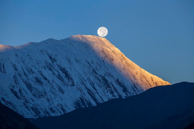 Beautiful landscape in Himalayas Annapurna region Nepal Full moon during a sunrise on the background of snowcapped mountains
