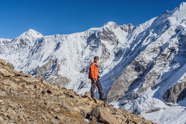 Beautiful landscape with mountains, blue huge glacier and a\
middle-aged mountaineer man against the background of mountains,\
glacier