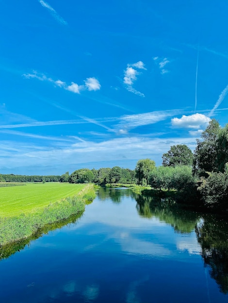 beautiful landscape with river and green field under blue sky in summer