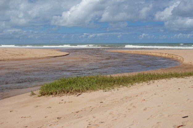 Beautiful landscape with a  a river meeting the sea  in a cloudy day