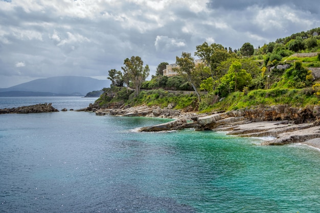 Фото Красивый пейзаж с морем, горами, скалами и скалами на берегу, зелеными деревьями и голубым небом