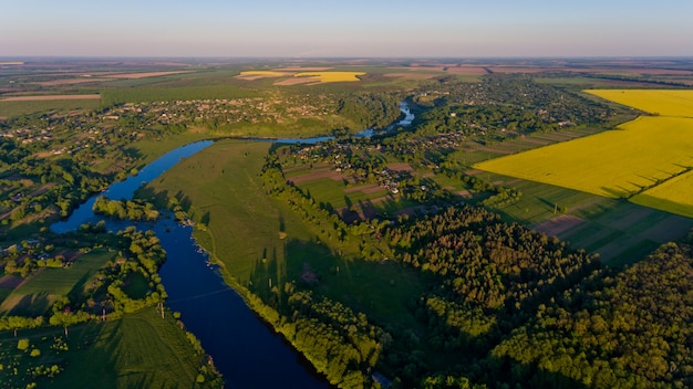 A beautiful landscape of a yellow field and a green forest and a river