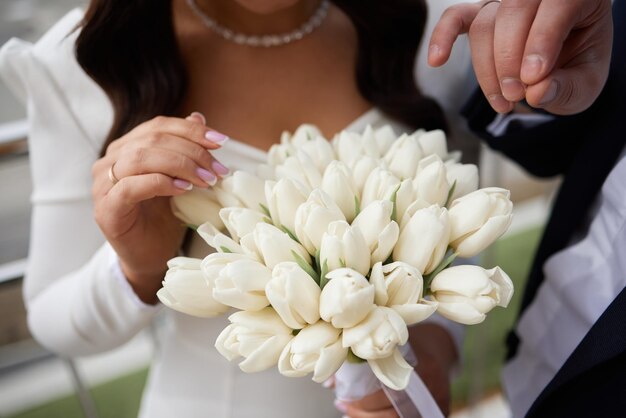 花嫁の手に白いチューリップの美しい大きな花束