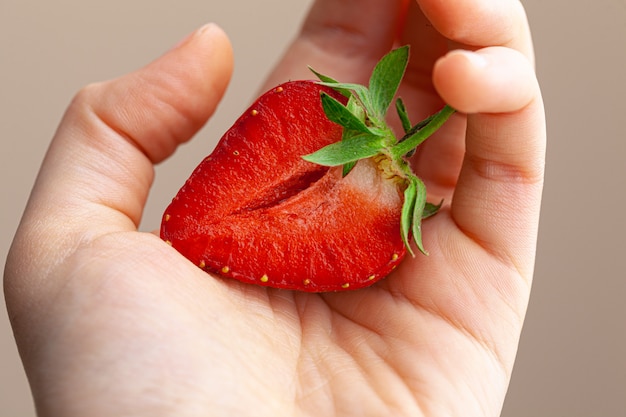 Beautiful large red strawberry in a hand. Close up.