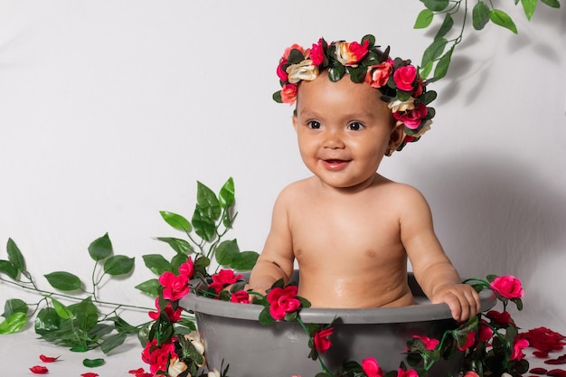 Beautiful latin baby girl 9 months old sitting on a bucket looking very happy