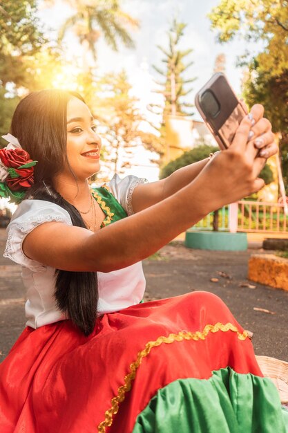 晴れた日に公園で自撮りをする伝統的なドレスを着た美しいラテンのティーンエイジャー