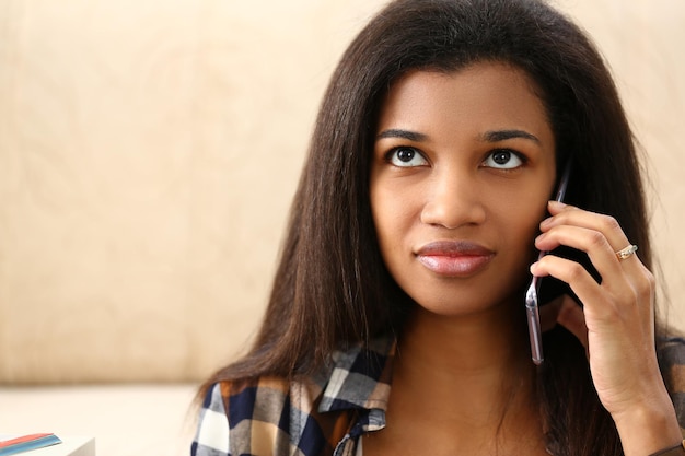 友人のアフロアメリカ人女性と携帯電話でチャットしている美しいラテン女性は目をそらします