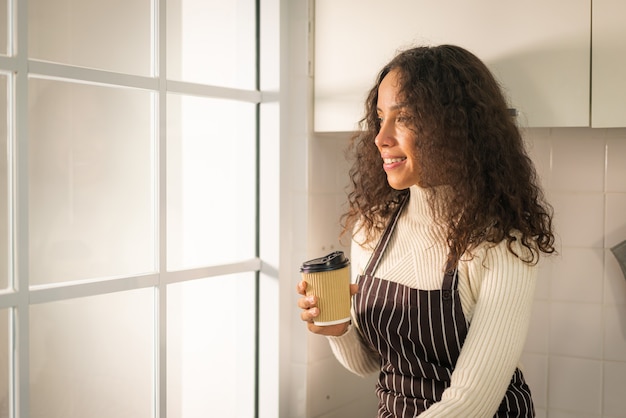 キッチンでコーヒーを飲む美しいラテン女性