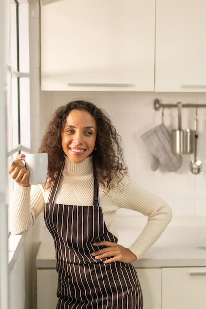 beautiful Latin woman drinking coffee in kitchen