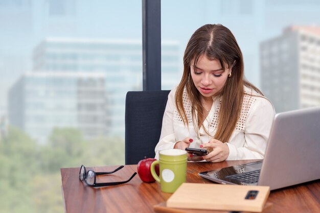 Bella donna latina che scrive con il suo cellulare