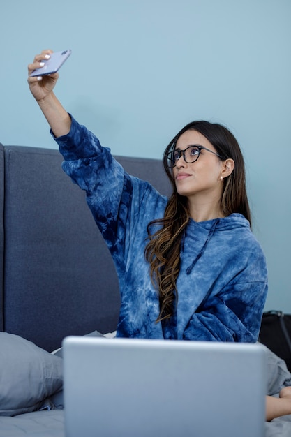 Beautiful latin woman wearing a sweatshirt taking a selfie in her bedroom