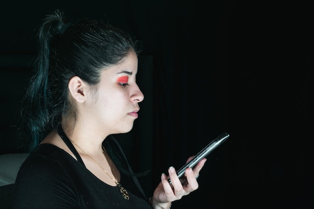Красивая латиноамериканка с зелеными волосами смотрит на свой мобильный телефон с выражением замешательства