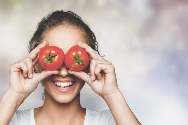 Beautiful laughing woman holding two ripe tomatoes