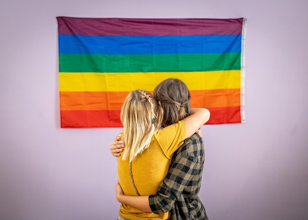 그들의 새로운 집 낭만적인 관계 성 평등 가족 생활 방식의 벽에 무지개 깃발을 들고 있는 아름다운 레즈비언 커플