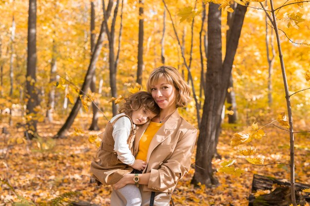 Beautiful lifestyle autumn photo mother and child walks evening in the park warm sunlight