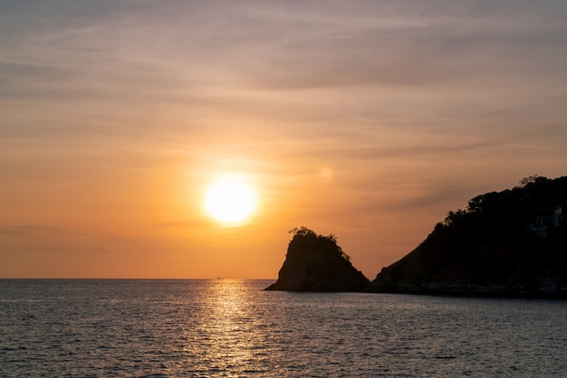 小さな島と劇的な空の海に沈む夕陽。