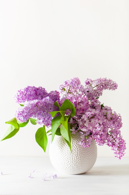 Фото Красивые сиреневые цветы в вазе на белом фоне