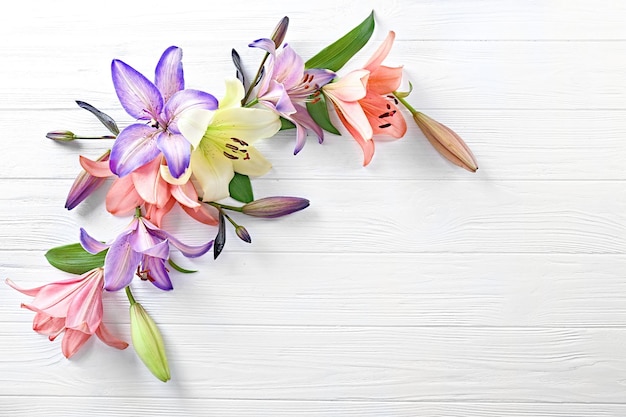 Beautiful lilies on light wooden background