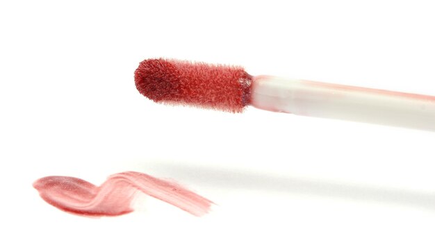 Beautiful lip gloss smear with brush isolated on white