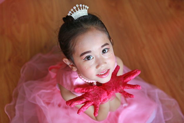 Beautiful little Asian ballerina girl in a pink tutu expression hands open.