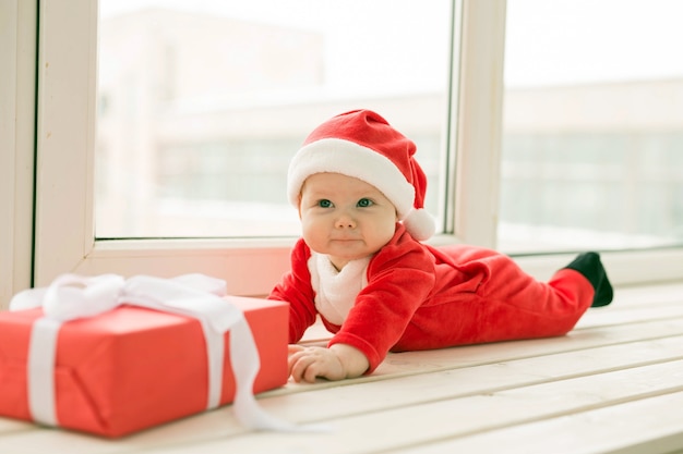 Beautiful little baby celebrates Christmas. New Year's holidays. Baby in a Christmas costume and in santa hat.