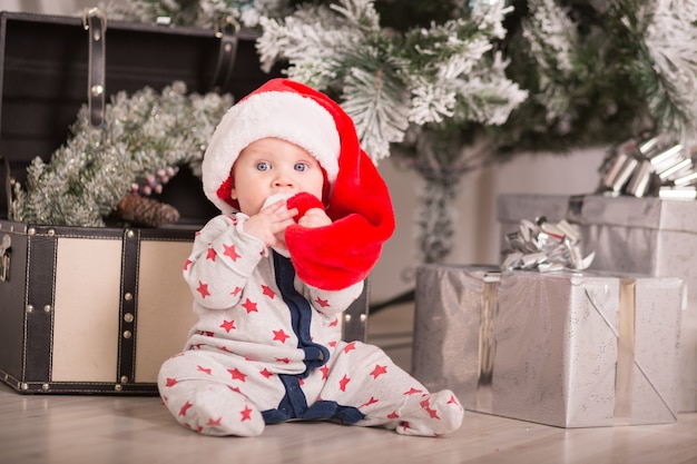 아름다운 작은 아기가 크리스마스를 축하합니다. 설날. 선물로 크리스마스 의상을 입은 아기