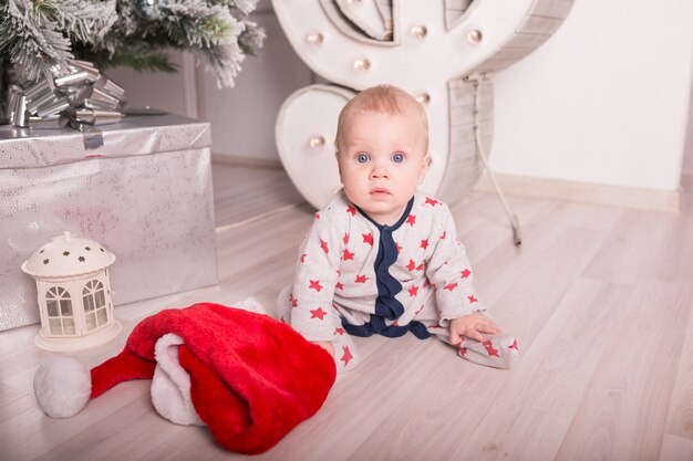 Beautiful little baby celebrates Christmas. New Year&#39;s holidays. Baby in a Christmas costume with gift