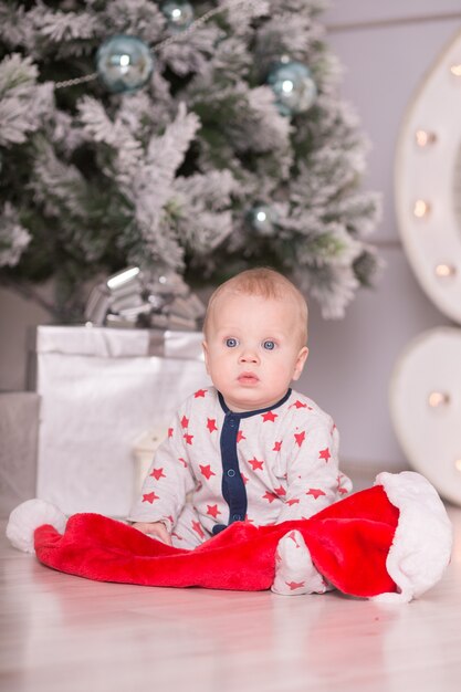 Beautiful little baby celebrates Christmas. New Year&#39;s holidays. Baby in a Christmas costume with gift