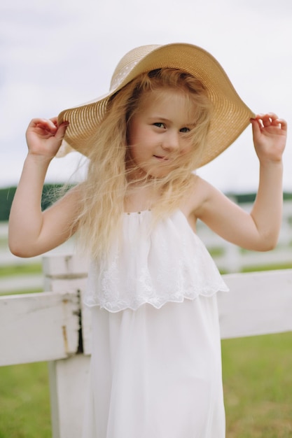 Beautiful little blonde girl on a ranch on a summer day.