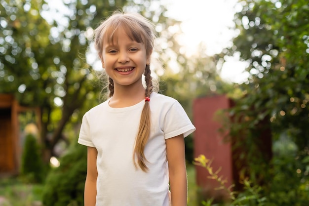 Beautiful little blonde girl with long hair in white T-shirt smiling