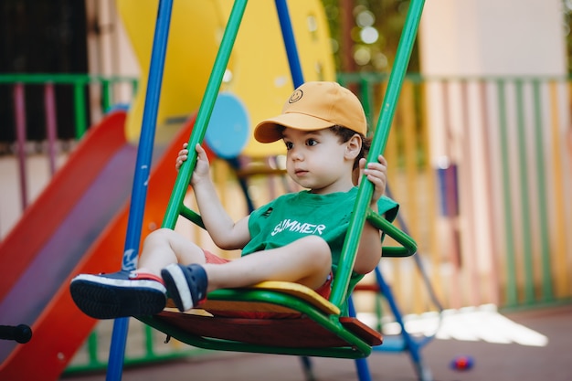 Beautiful little boy spinning on a summer swing with space for text