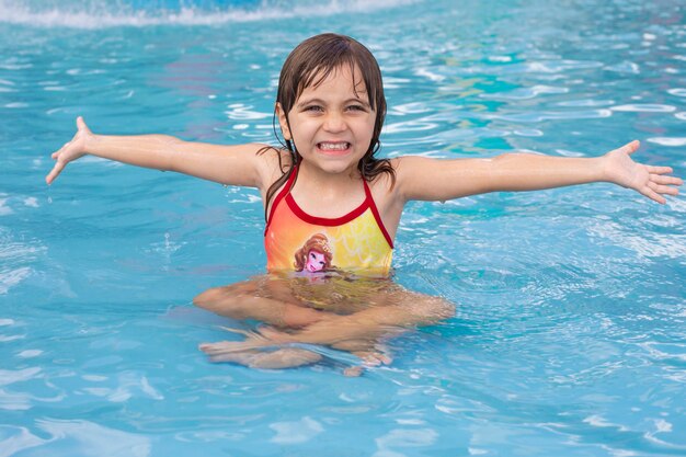 Beautiful little caucasian girl in swimming pool refreshing in summer