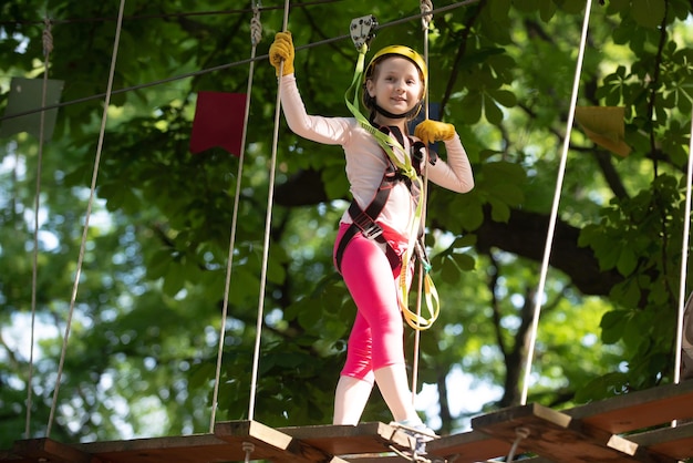 Beautiful little child climbing and having fun in adventure Park Cargo net climbing and hanging log