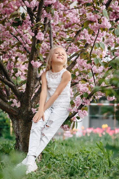 Beautiful little child girl with sakura flowers